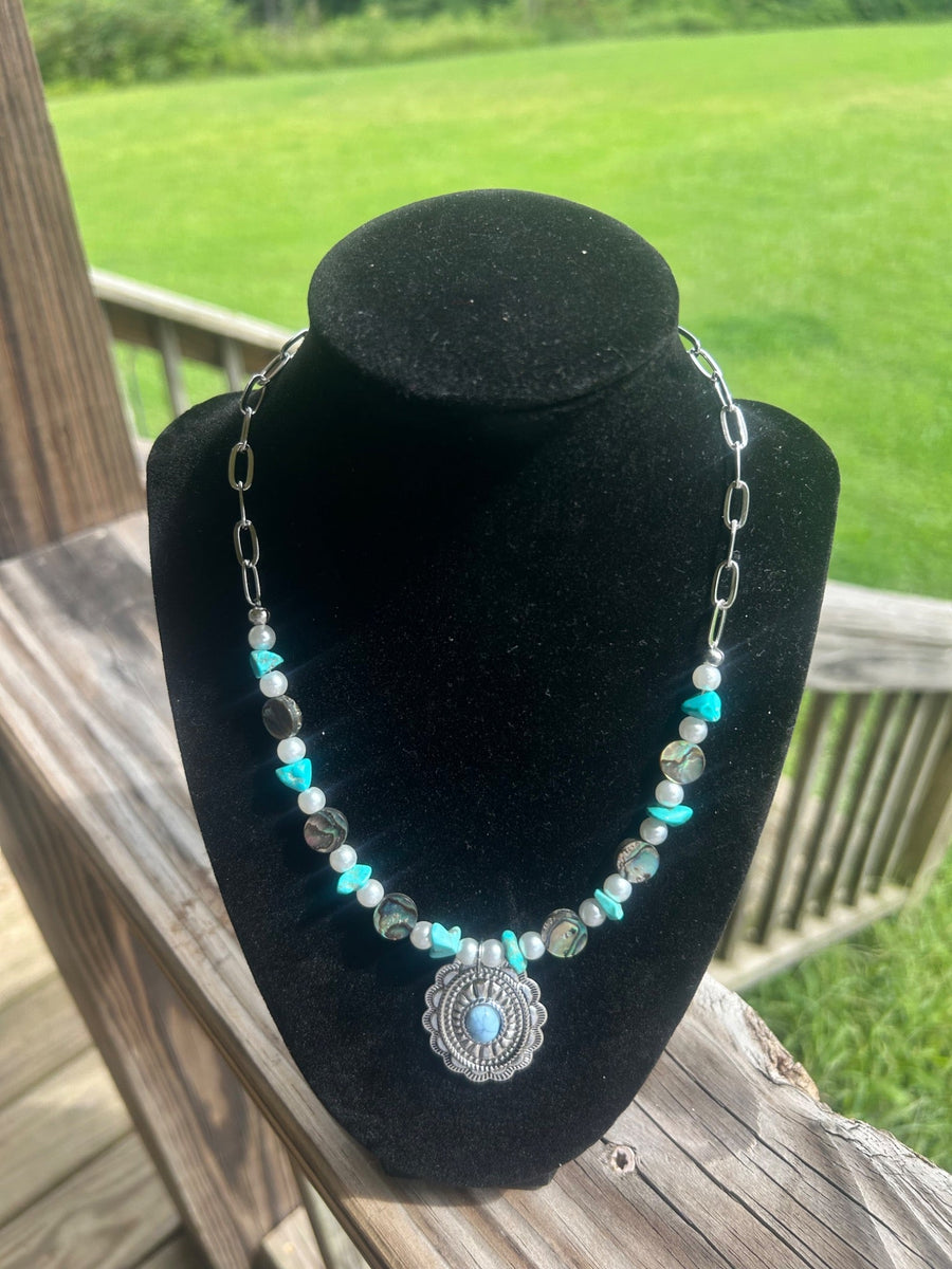 Turquoise-color pearl-style handmade necklace with silver-tone concho-style focal.