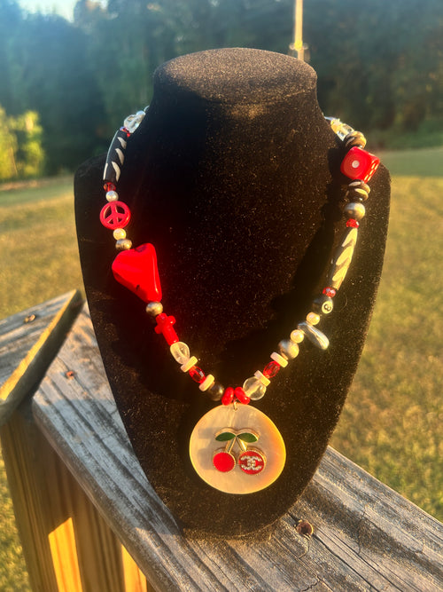 Handmade red, black and white eclectic statement necklace with mixed beads, peace sign accent and cherry focal pendant.